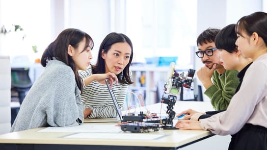 Employees around a table consulting their screen and discussing