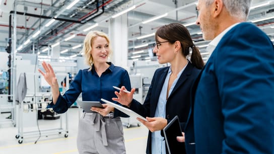 Businesswomen having discussion by businessman at automated factory