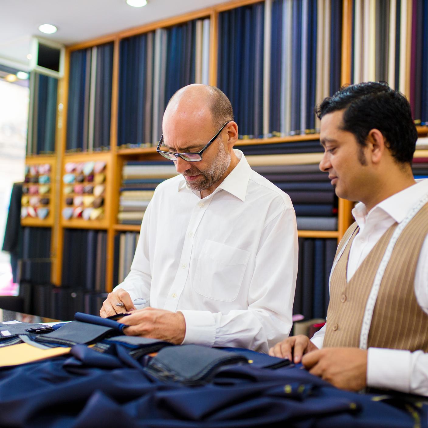 Client et tailleur regardant des échantillons de tissus dans un atelier de tailleur