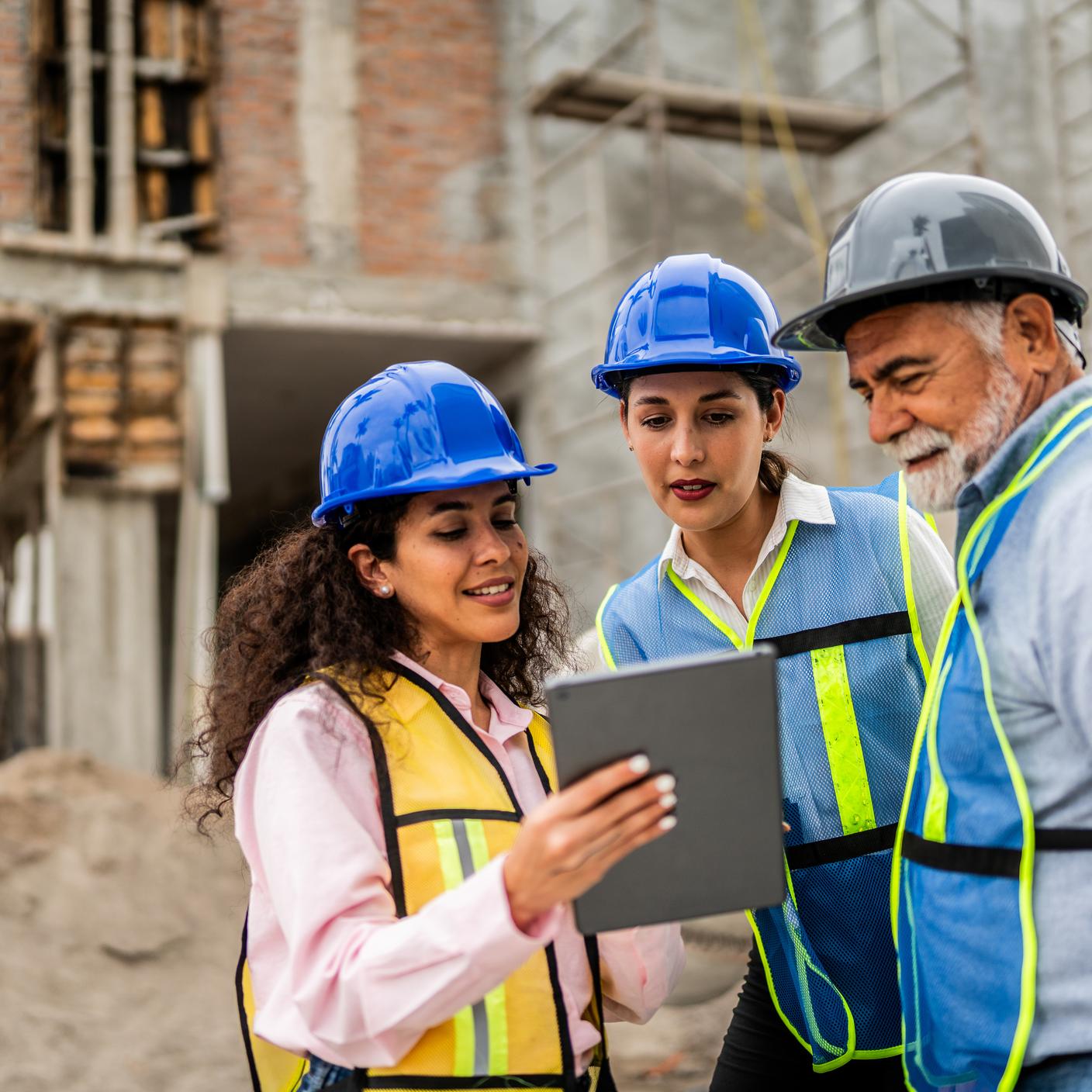 oworkers talking and using digital tablet on construction site