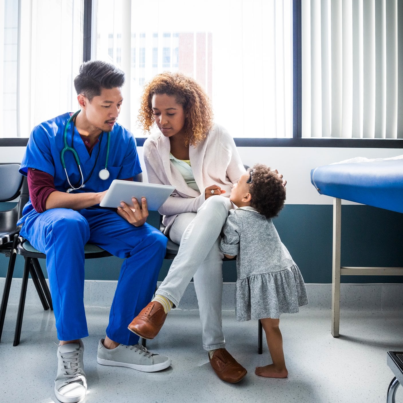 Enfermeira mostra tablet digital para mãe de criança pequena no hospital