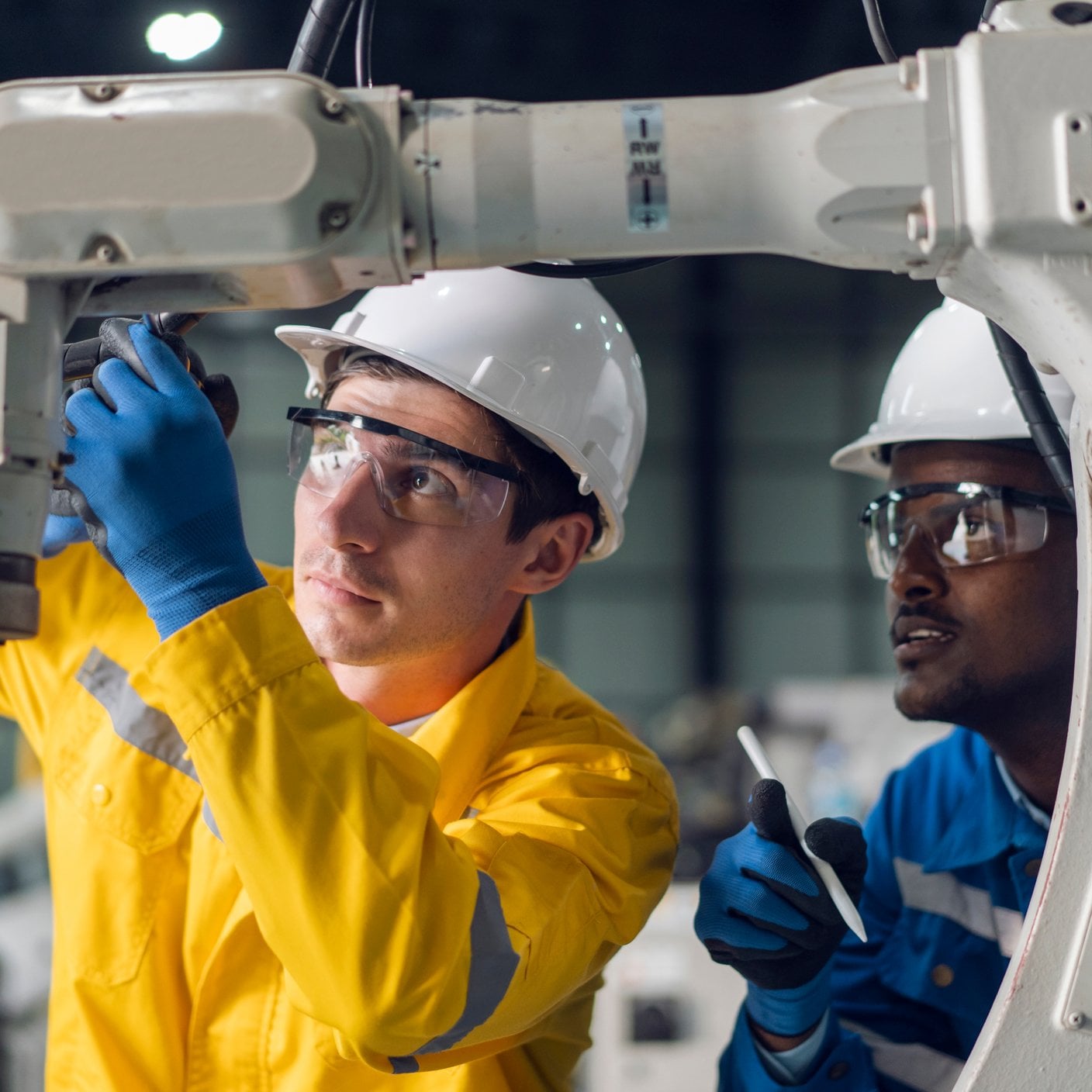 Group of male engineers working on automatic robotic arm machine in a factory