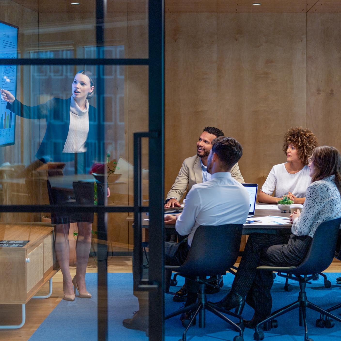 Woman giving a big data presentation on a tv in a board room. 