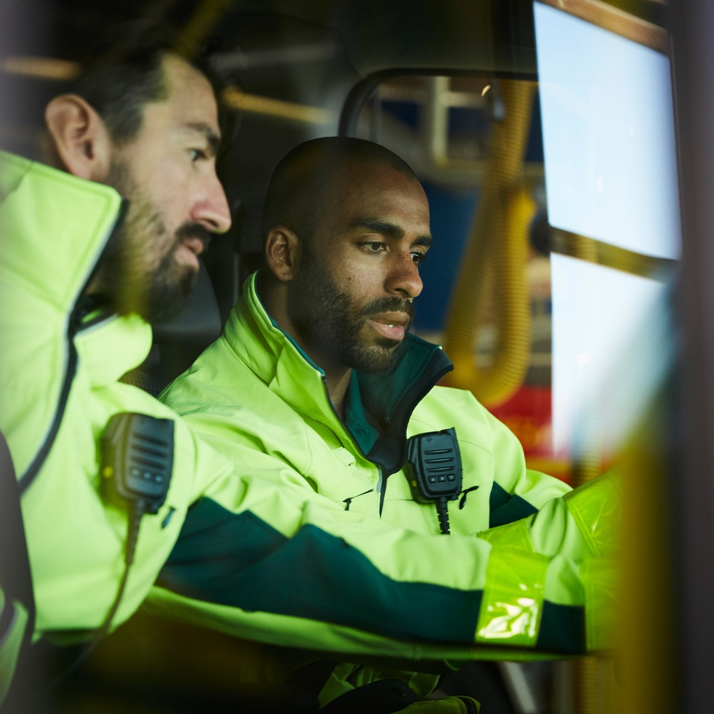 Male paramedics discussing while sitting in ambulance at parking lot