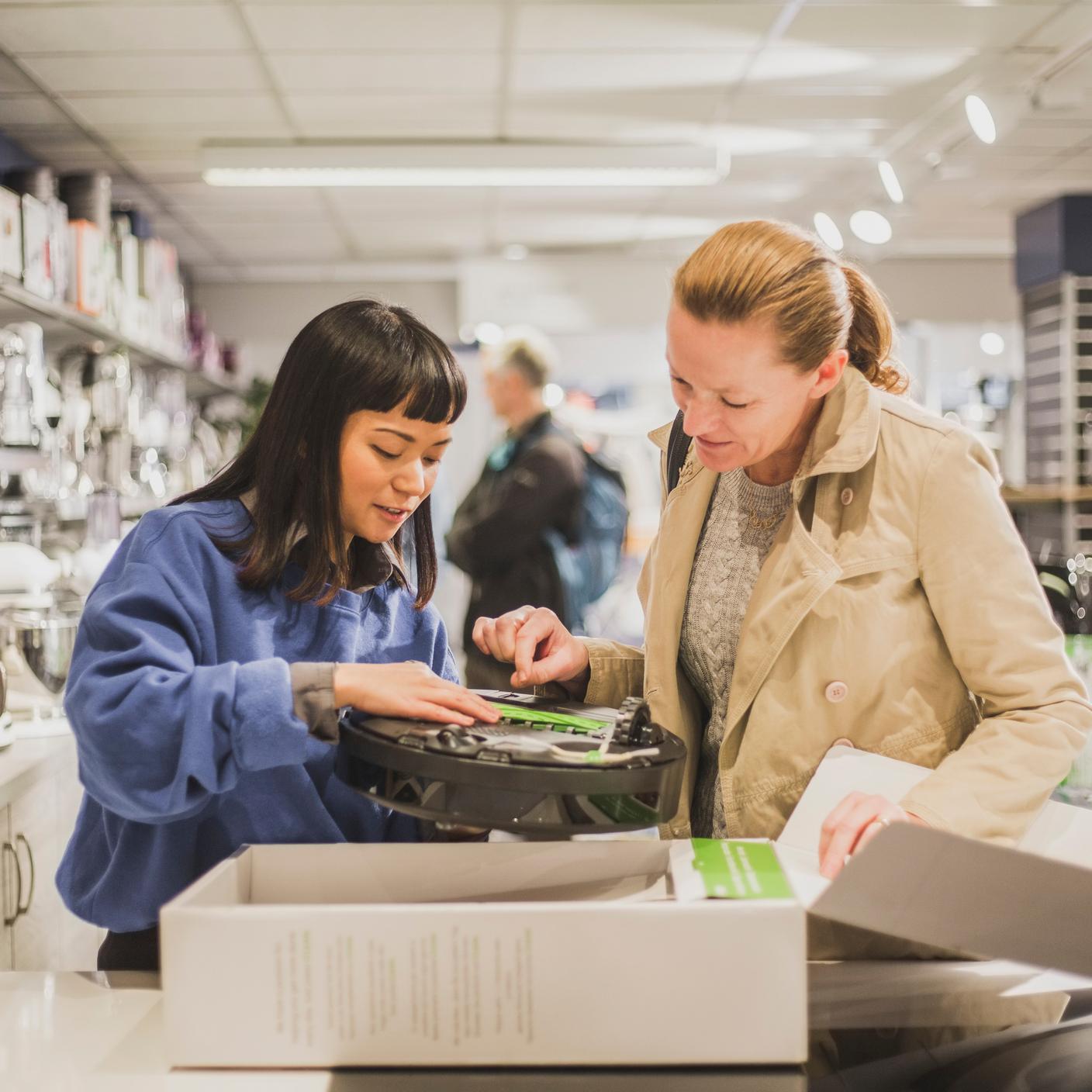 Saleswoman showing appliance to customer in store