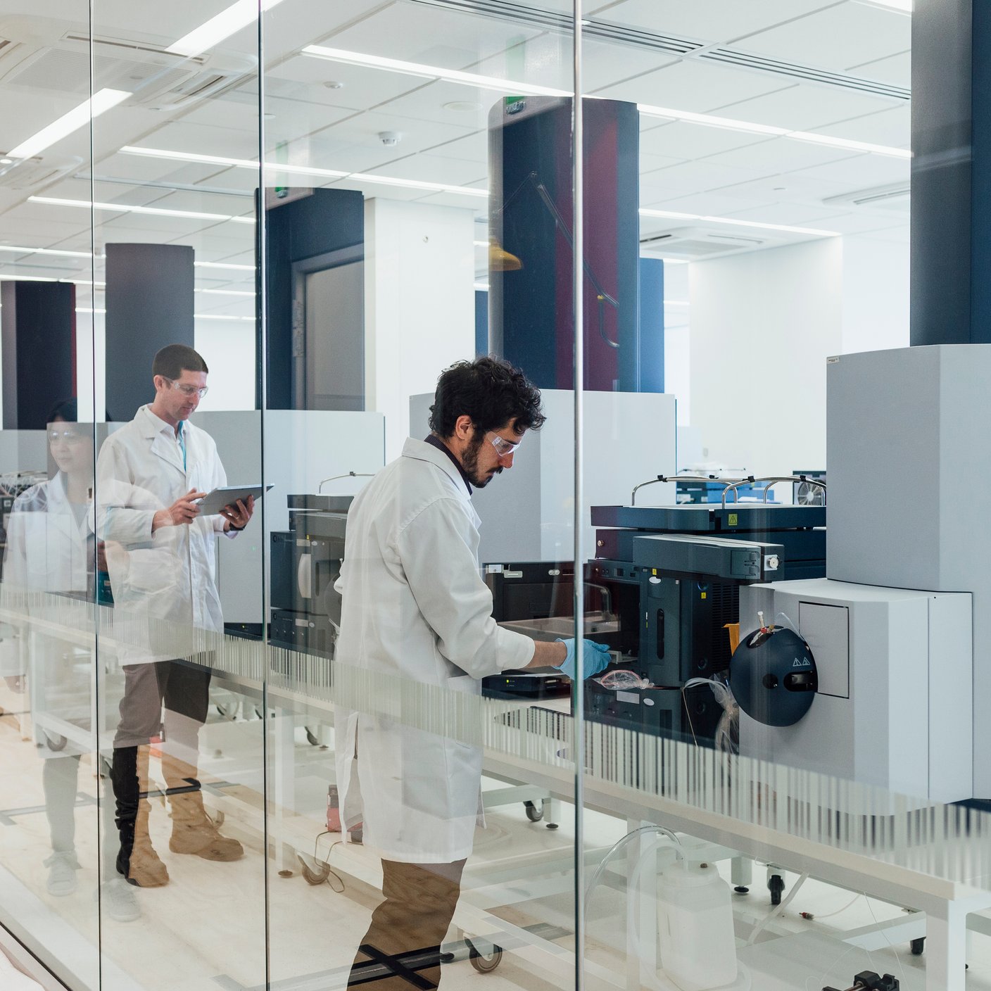 A female scientist walks down a corridor and observes her colleagues.