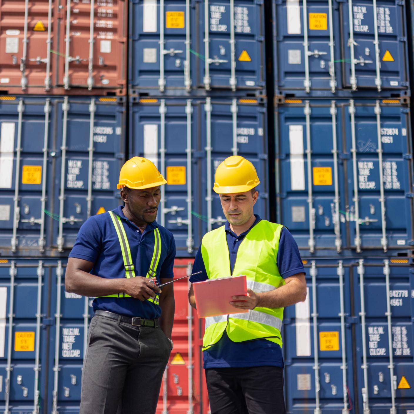Two Commercial dock workers examining and confirm shipment at cargo container yard. Logistic and Transportation, Global Business concept, Freight forwarder business.