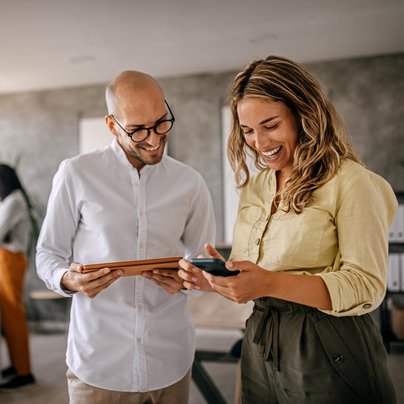 Woman and man in office viewing tablet and mobile