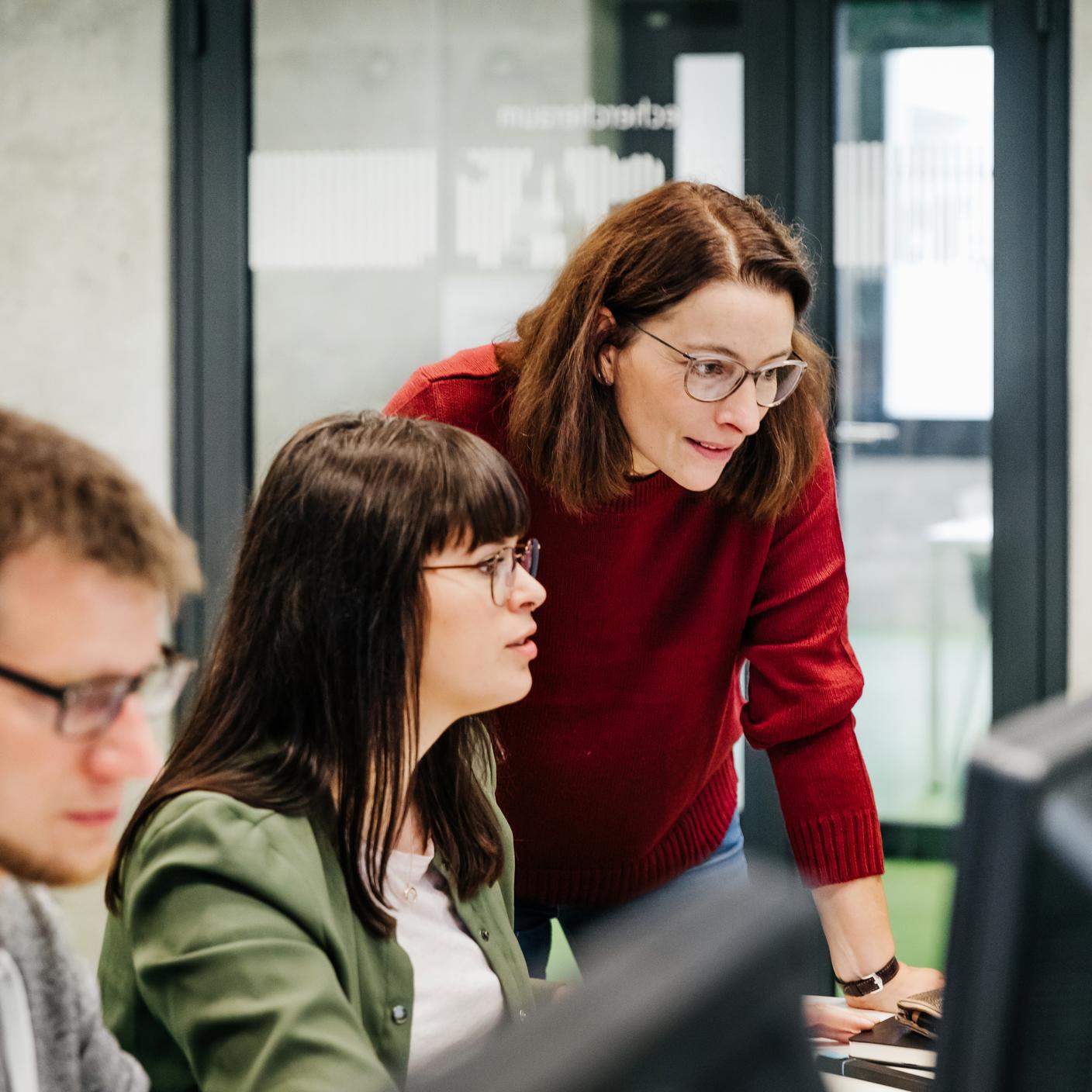 A teacher helping a student with her computer work during a seminar at university
