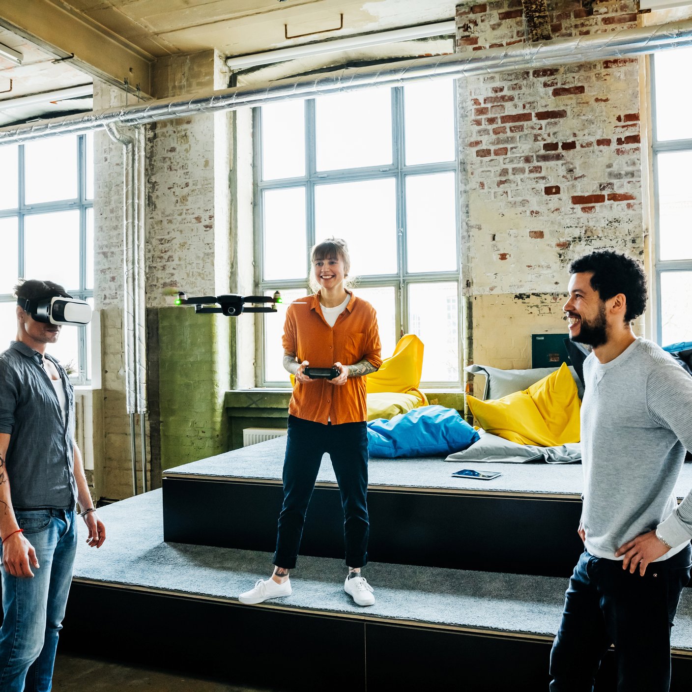 Young start up business people flying a drone inside a big office