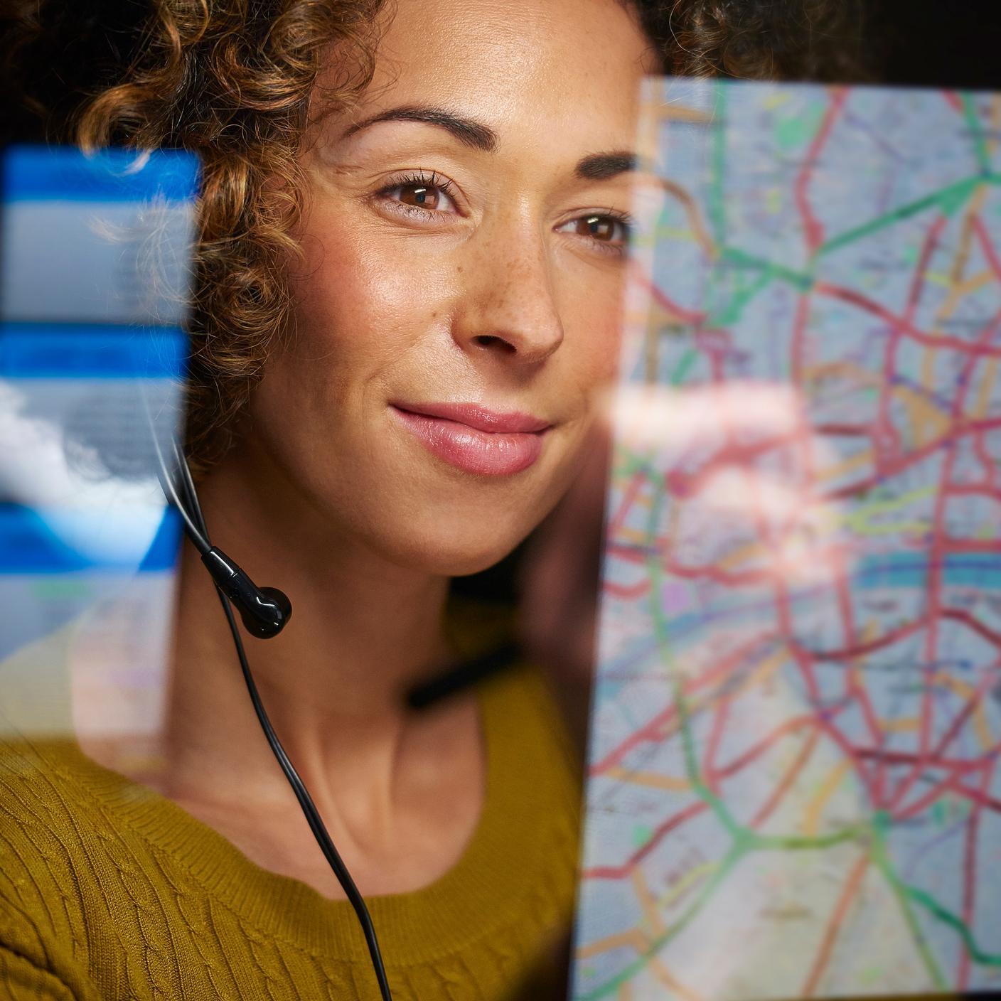 Una trabajadora de logística organiza el envío de mercancías en su mapa digital interactivo mientras habla por sus auriculares.