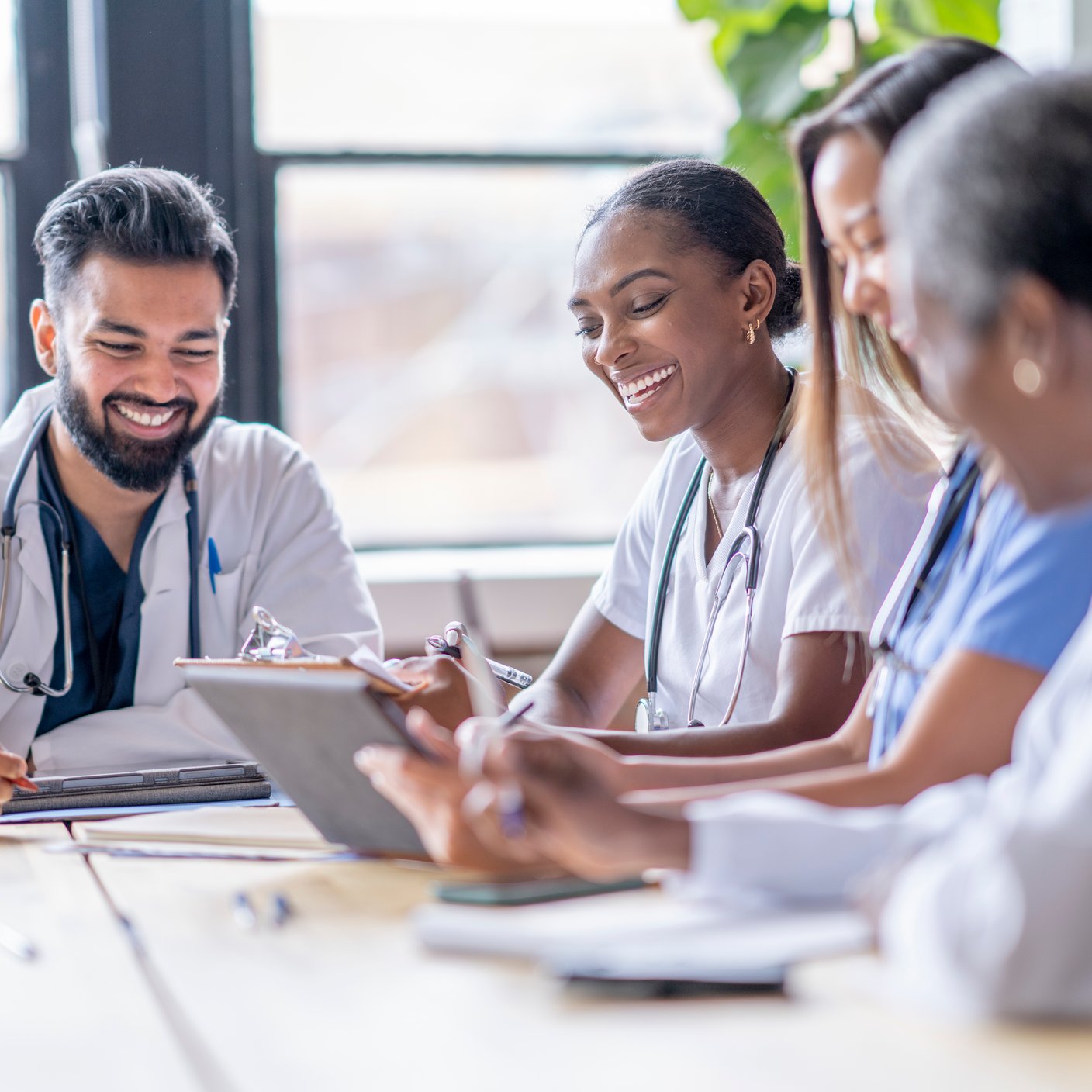 A small group of four medical professionals sit around a boardroom table