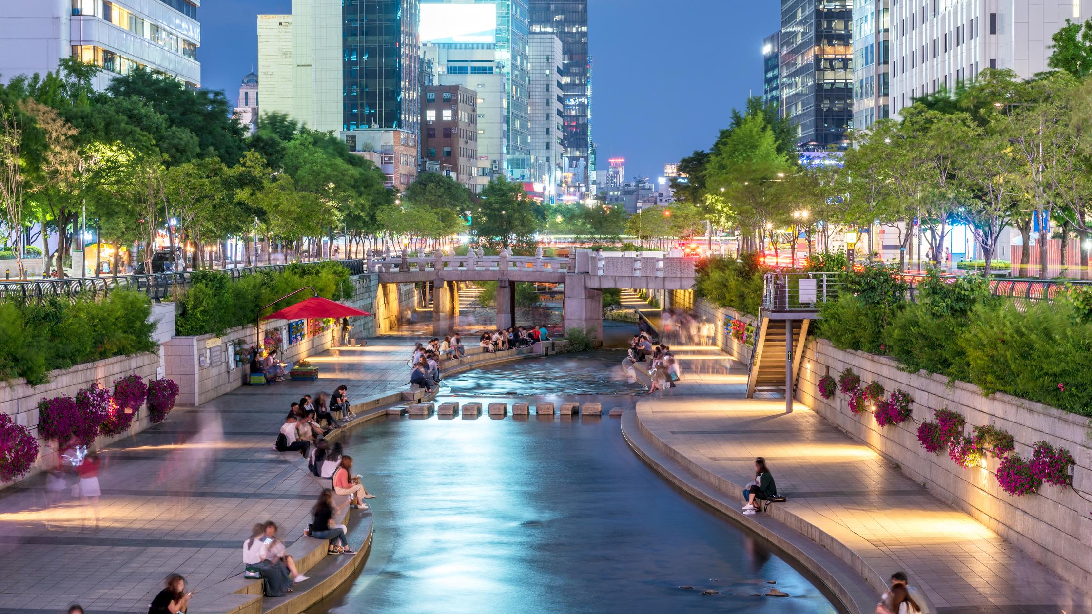 built environment people sitting by river on digital devices