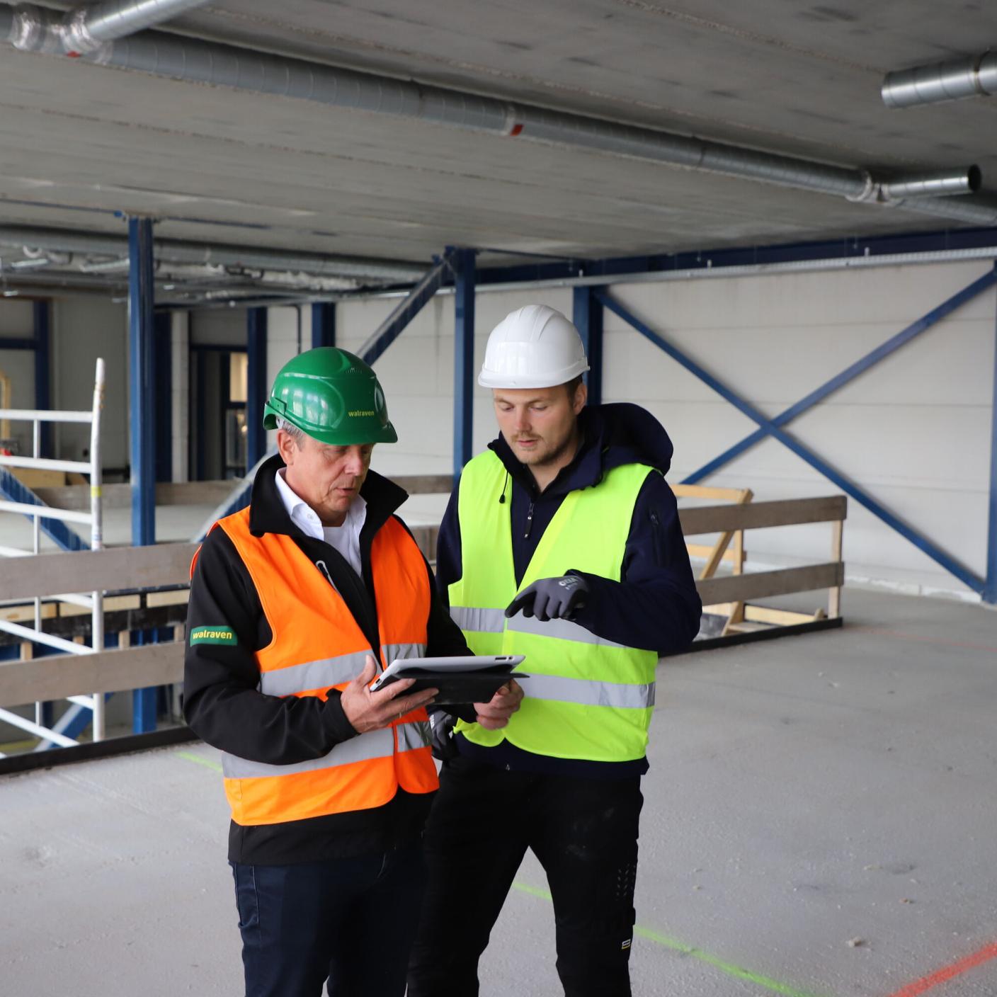 Two men in hard hats in warehouse.